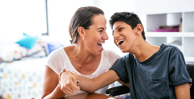 Disabled Latino teenager with Celebral Palsy and mother laughing.